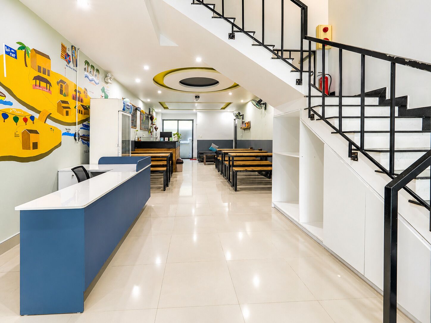 A modern interior with a reception desk, seating area, and a staircase.