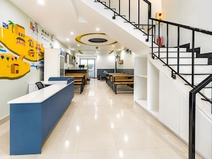 A modern interior with a reception desk, seating area, and a staircase. - Two Horses Hostel (Hoi An)