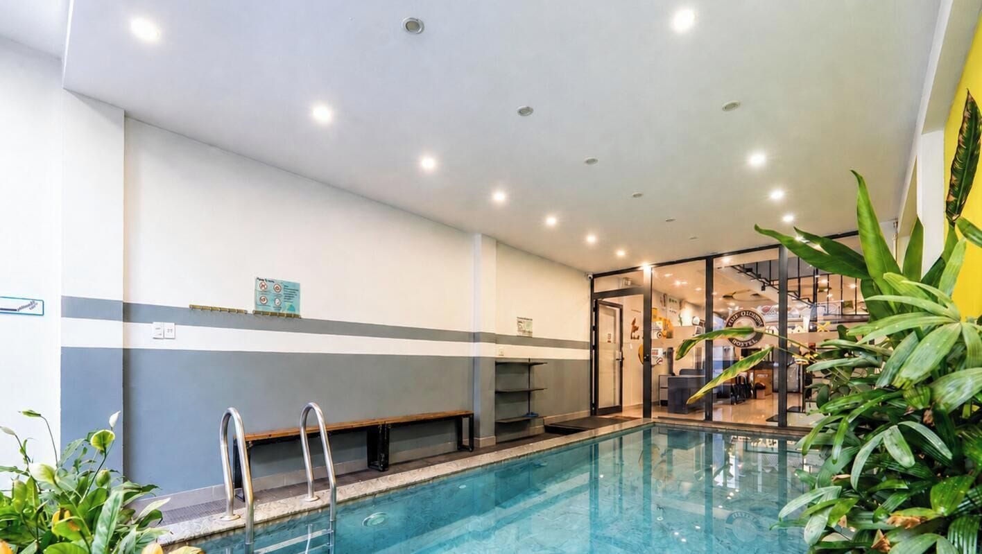 An indoor swimming pool with a clear view of the adjacent restaurant and a modern interior design.