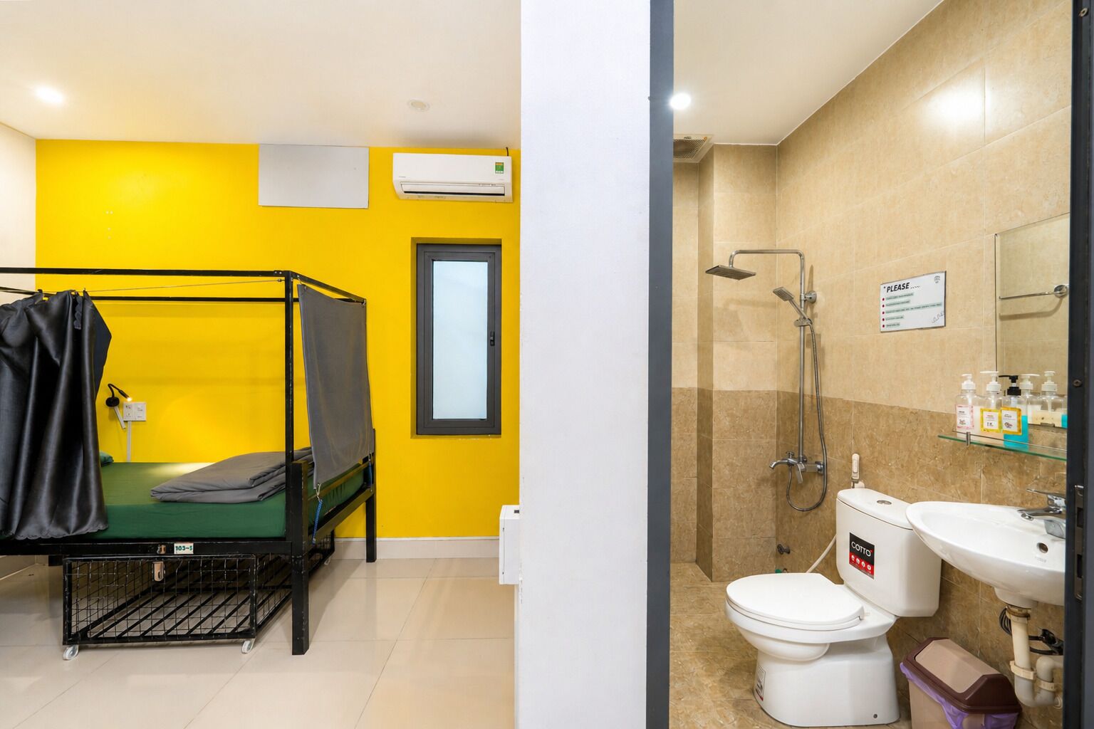 A room with a bunk bed, a window, and a shower area with a toilet and sink.