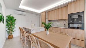 A modern kitchen with wooden cabinets, a marble countertop, and a built-in oven. - LXR Dalí 1-Bedroom Beachfront (Fuengirola)