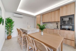 A modern kitchen with wooden cabinets, a marble countertop, and a built-in oven. - LXR Dalí 1-Bedroom Beachfront (Fuengirola)
