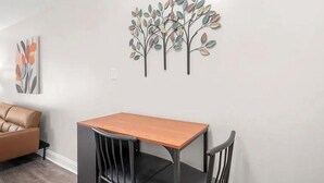 Et spiseområde med et bord, stole, en sofa og billedkunst på væggen.