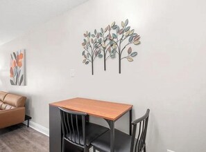 Un espace repas comprenant une table et des chaises, un canapé et des œuvres d’art murales.