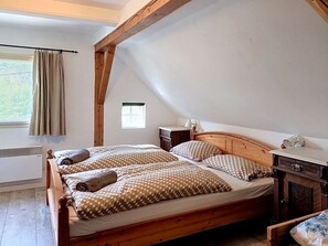 Un dormitorio con una cama de madera, una mesita de noche, un aparador y una ventana con cortinas.