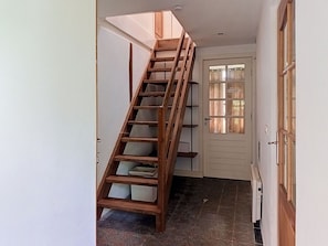 Un escalier en bois avec une rampe, menant à une porte dotée d’une fenêtre.