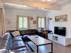 Un salon comprenant un canapé en cuir, une table basse, un téléviseur et un bureau avec une chaise.