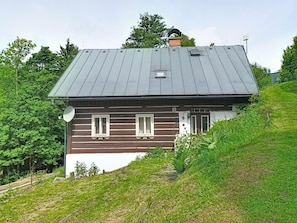 Une maison avec un toit en pente, une cheminée et une antenne parabolique.