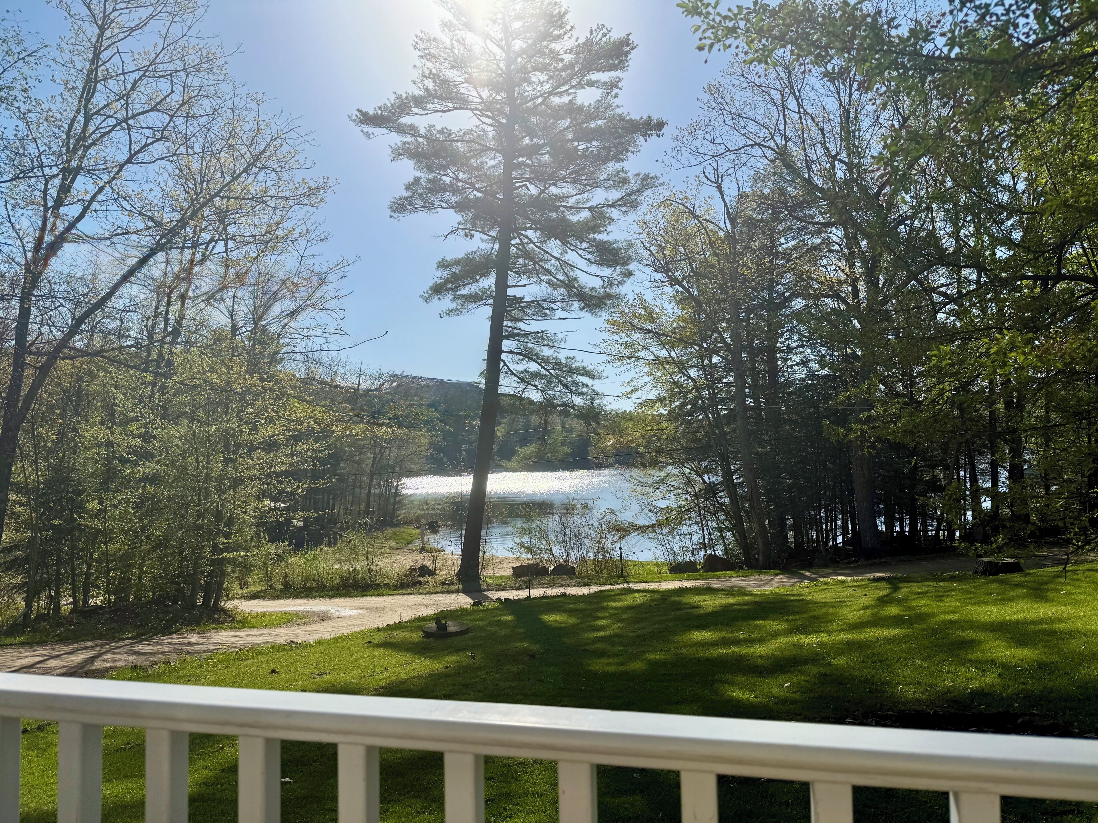 A deck with a view of a lake surrounded by trees.