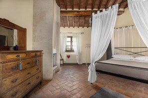 Una camera da letto con un letto, una cassettiera in legno, un termosifone e una finestra con tende.