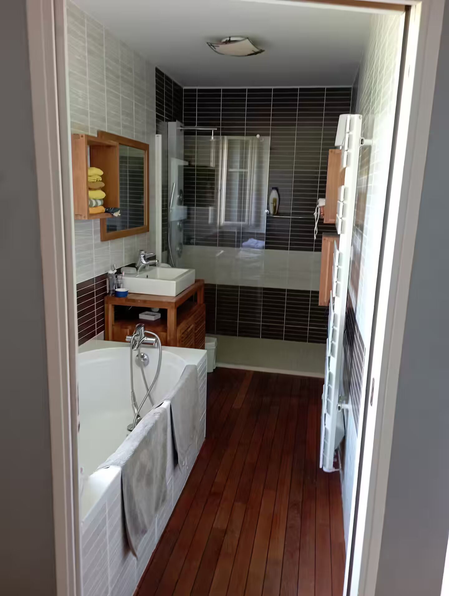 Een moderne badkamer met een bad, een wastafel met spiegel en een douche.