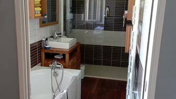 Een moderne badkamer met een bad, een wastafel met spiegel en een douche.