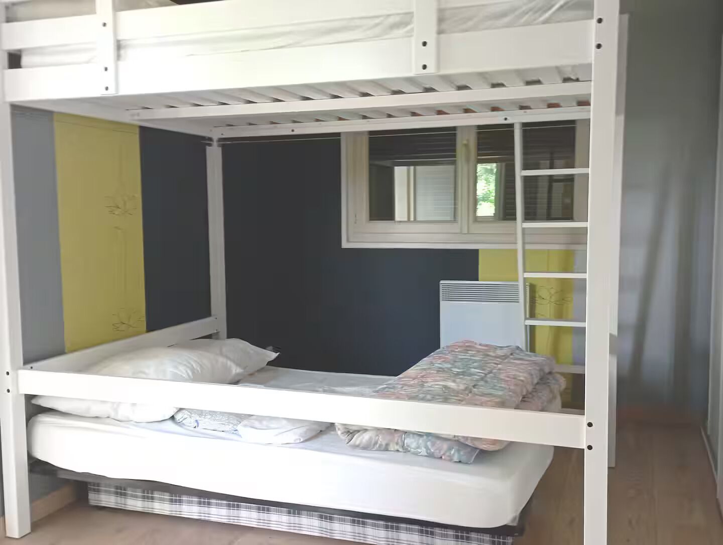 A bunk bed with a lower bunk, a window with blinds, and a radiator.