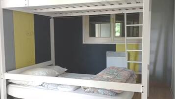 A bunk bed with a lower bunk, a window with blinds, and a radiator.