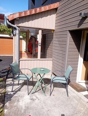 Un área de estar al aire libre con una mesa, sillas, una ventana y una puerta.