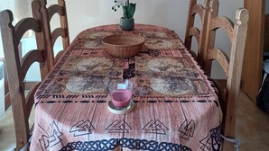 A dining table with a patterned tablecloth, a candle, and a potted orchid. - Cosy studio with terrace (Gréolières)