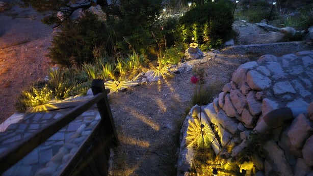 A garden pathway with a wooden bench, a stone wall, and illuminated garden lights. - Cosy studio with terrace (Gréolières)
