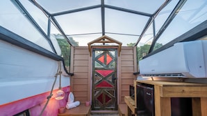 Een compacte, goed verlichte kamer met een houten deur, een zithoekje, een houten tafel en een ingebouwde airconditioning.