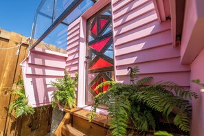 A pink house with a window featuring a geometric design. - Exotic Pink Boat Home by the Beach w/ AC! (Vieques)