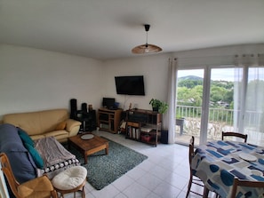 A living room with a sofa, coffee table, TV, and a balcony with a view.