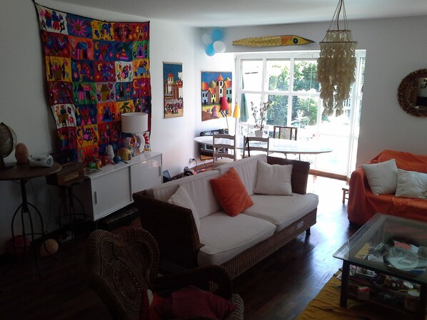 Ein Wohnzimmer mit einer Couch, Sesseln, einem Glastisch, einem Essbereich mit Tisch und Stühlen sowie einem großen Fenster mit Blick.