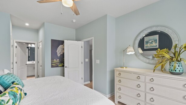 Ein Schlafzimmer mit Bett, Kommode, Spiegel und Deckenventilator.