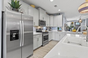 A modern kitchen with stainless steel appliances, white cabinetry, and a central island with a sink.