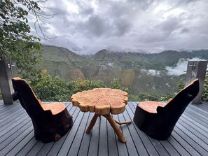 Mesa y sillas de madera en una terraza con vista a la montaña.