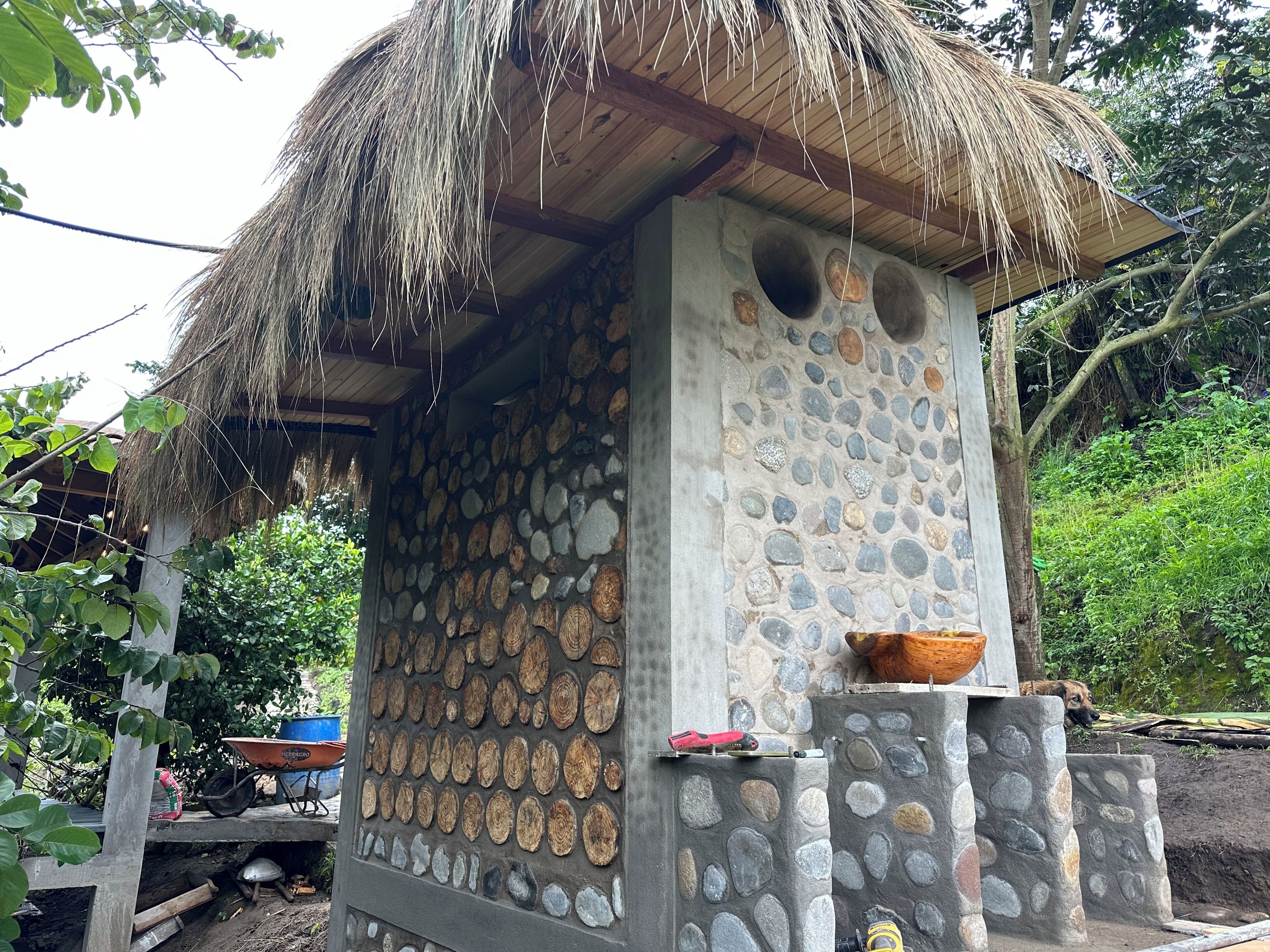 Una construcción rústica con techo de paja, paredes de piedra y una viga de madera.