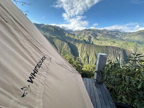 Tienda de campaña con el rótulo 'WHITE DUCK', con vista a montañas verdes y cielo despejado.