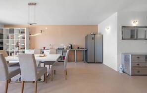 Eine moderne Küche mit Essbereich, weißen Schränken und einem Einbaukühlschrank.