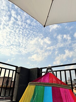 Una carpa colorida en un balcón, con un cielo despejado al fondo.