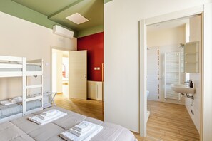 A hotel room with bunk beds, a bathroom with a sink and towel rack, and a wooden floor. - Large apartment in the center - Lake Como and Station 5 min (Lecco)