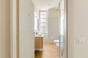 A narrow hallway leading to a bathroom with a wooden floor, a sink, and a toilet. - Large apartment in the center - Lake Como and Station 5 min (Lecco)