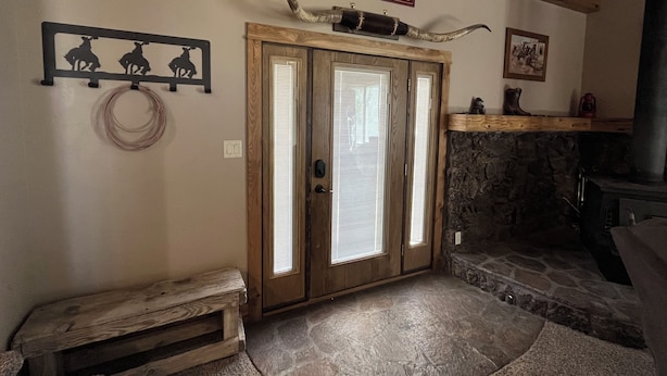 A room with a wooden door, a stone fireplace, a wooden bench, and a sign above the door.