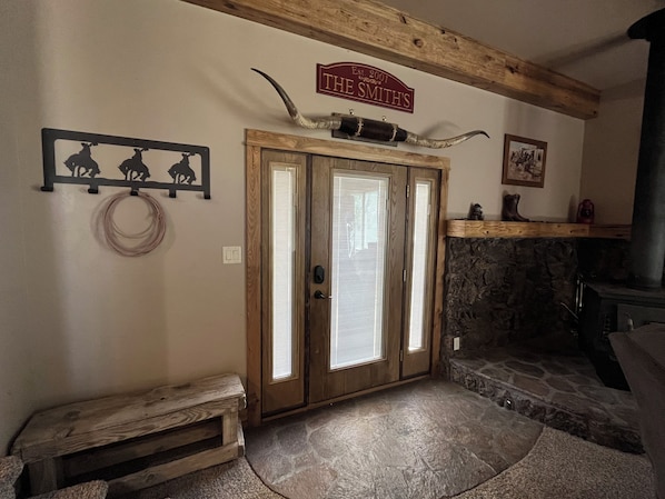 A room with a wooden door, a stone fireplace, a wooden bench, and a sign above the door.