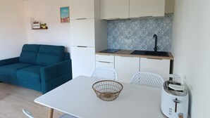 Un espacio habitable compacto con kitchenette, una mesa de comedor, un sofá y un tostador.