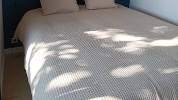 A bed with a blue headboard, two beige pillows, and a white quilted bedspread.