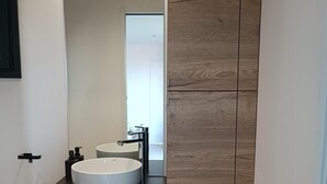 Un baño moderno con encimera negra, dos lavamanos y pared de paneles de madera.