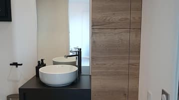 A modern bathroom with a black countertop, two sinks, and a wooden panel wall.