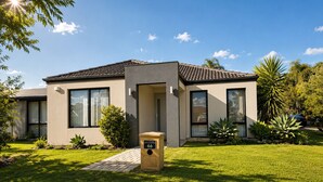 A modern two-story house with a front yard, a mailbox, and a clear sky. - Modern Oasis | 3BR Home (Bassendean)