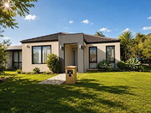 A modern two-story house with a front yard, a mailbox, and a clear sky. - Modern Oasis | 3BR Home (Bassendean)