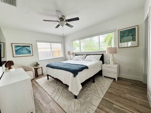 A bedroom with a bed, bedside tables, a ceiling fan, a window, and a rug. - Luxury beach house, heated pool, 10 minute walk to beach! (Pompano Beach)