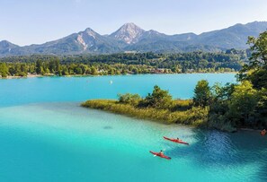 A lake with kayaks, surrounded by mountains and trees. - Luxury Apartment in Villach (75 m²) (Villach)