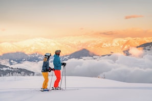 Two people skiing on a snowy mountain with a sunset in the background. - Luxury Apartment in Villach (75 m²) (Villach)