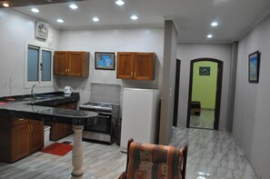 Une cuisine avec des meubles de rangement en bois, une cuisinière à gaz, un réfrigérateur et un évier.