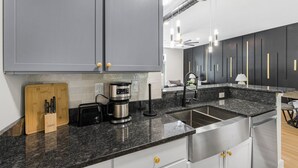 A modern kitchen with grey cabinets, a granite countertop, a coffee maker, and a toaster. - Luxury 1BR Loft in Atlanta’s Vibrant Heart. (Atlanta)