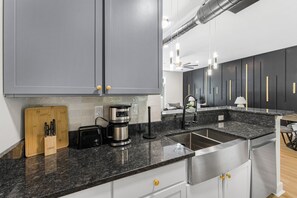 Eine moderne Küche mit grauen Schränken, einer Granitarbeitsplatte, einer Kaffeemaschine und einem Toaster.