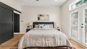 A bedroom with a bed, a ceiling fan, a painting, and a large window. - Luxury 1BR Loft in Atlanta’s Vibrant Heart. (Atlanta)