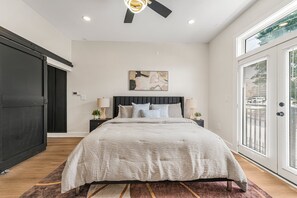 Ein Schlafzimmer mit Bett, Deckenventilator, Gemälde und großem Fenster.